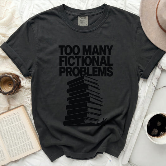 T-shirt with "Too Many Fictional Problems" text and stack of books.