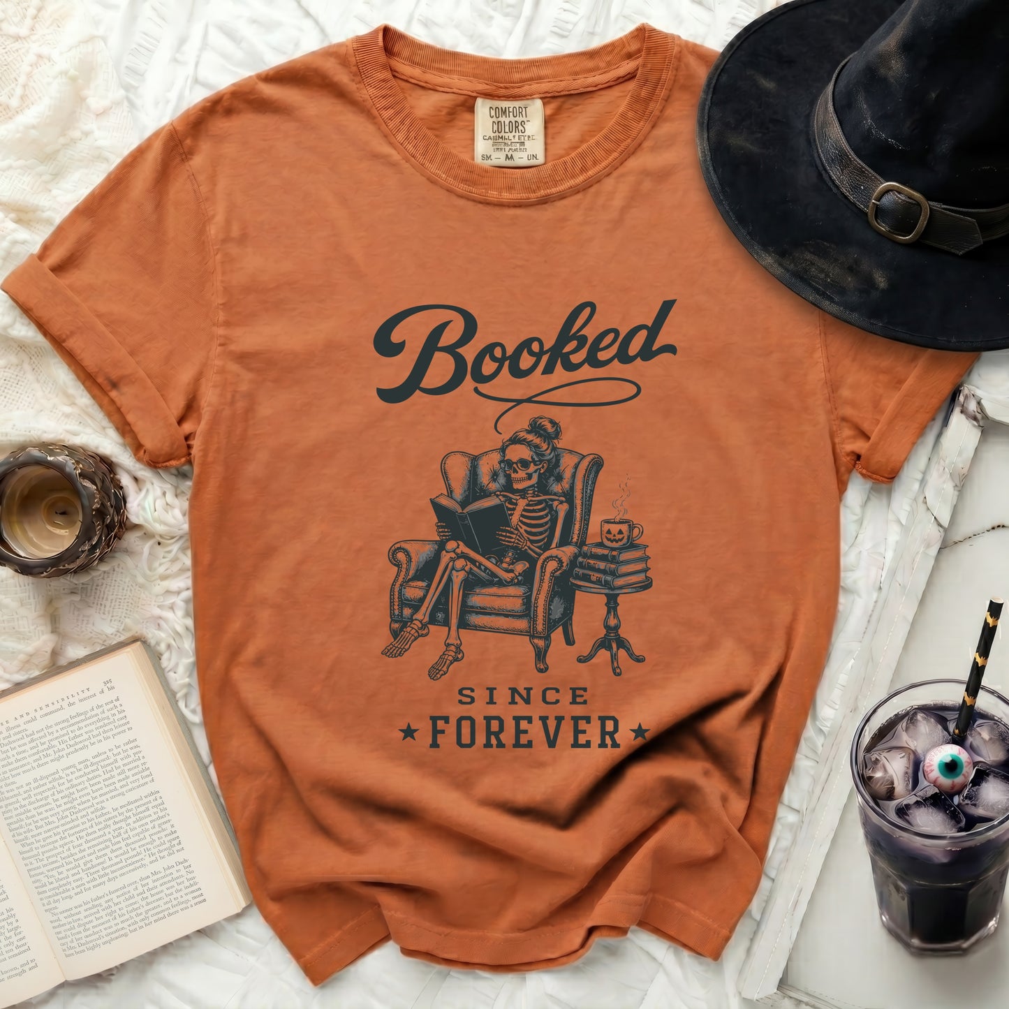 Orange t-shirt with "Booked Since Forever" skeleton reader graphic.
