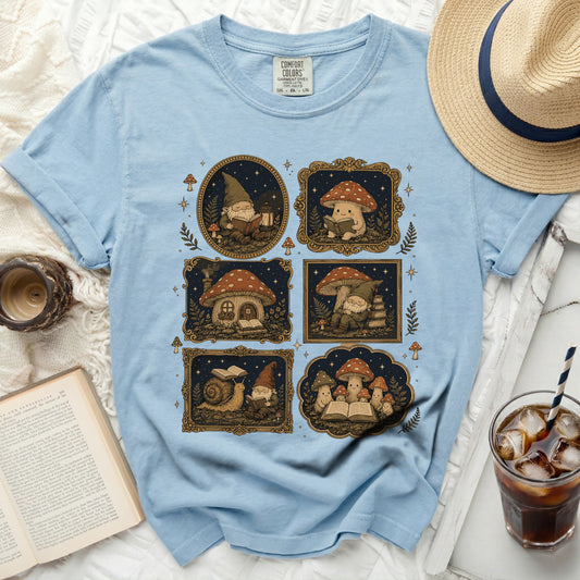 Light blue t-shirt with five decorative framed illustrations of gnomes and mushrooms.