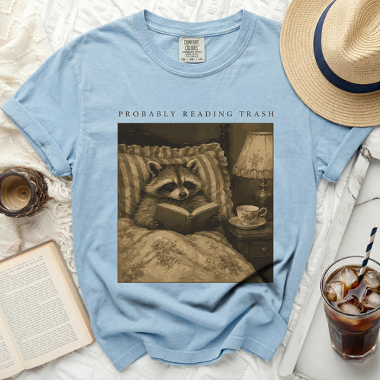 Light blue t-shirt with graphic of raccoon reading "PROBABLY READING TRASH".