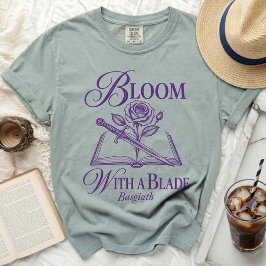 Light green t-shirt with purple "Bloom With A Blade Basgiath" text and rose design.