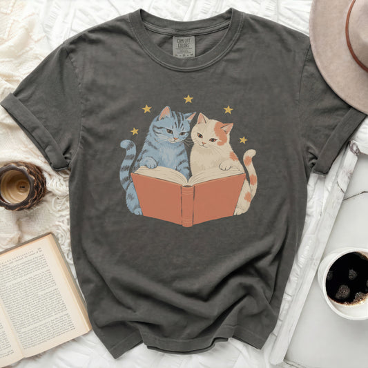 Two cats reading a book with stars above, on a dark gray t-shirt.
