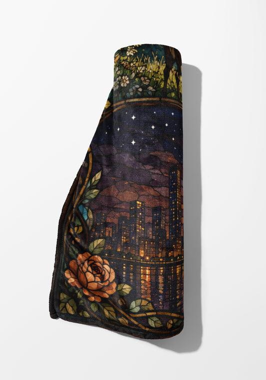 Rolled blanket with stained glass design of rose and city at night.