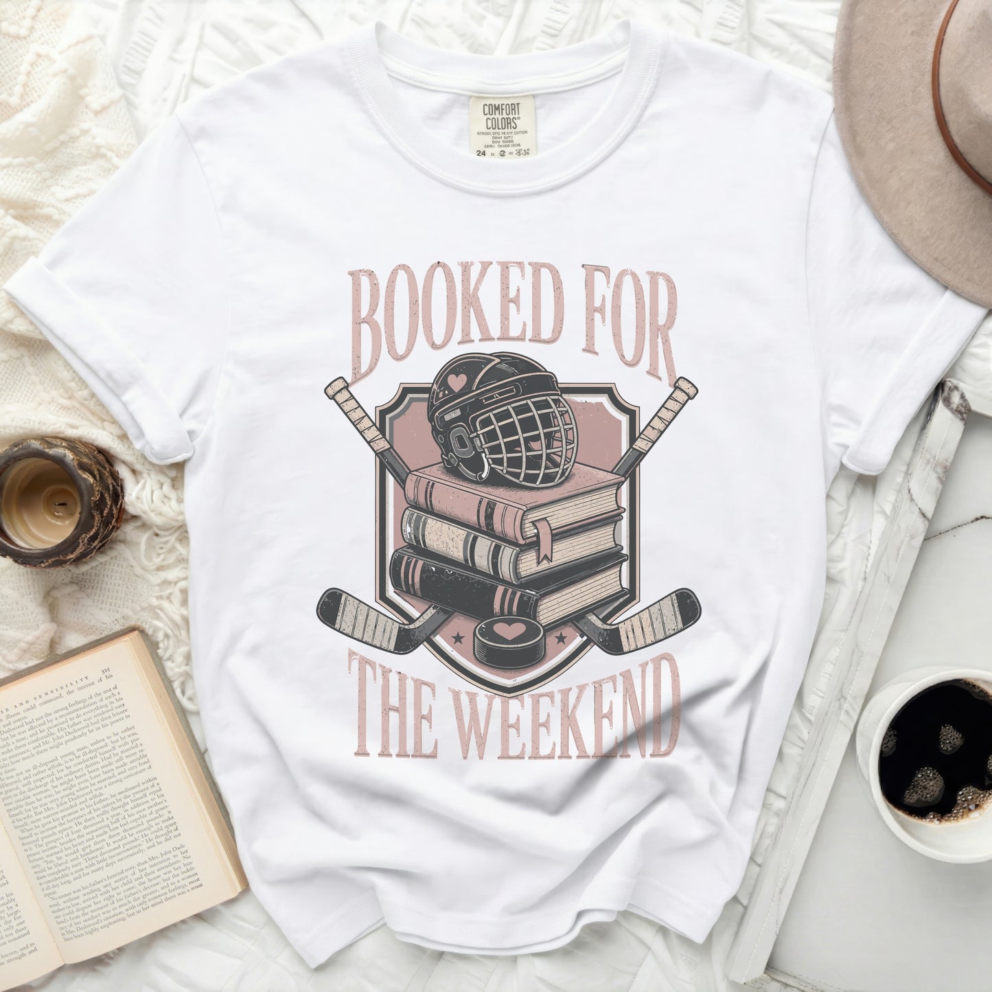 White t-shirt with "Booked for the Weekend" text and hockey gear graphic.