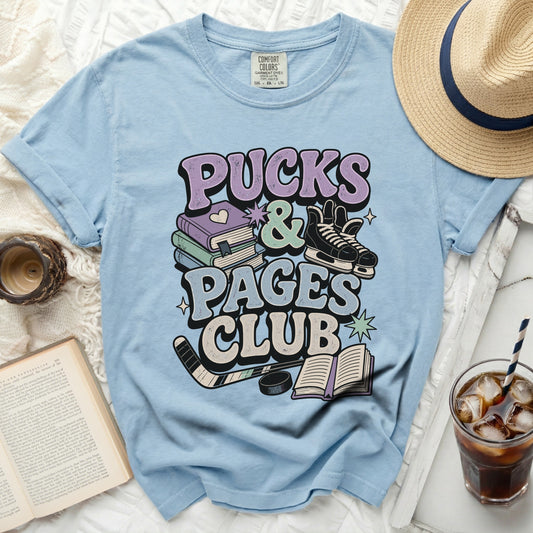 Light blue t-shirt with "Pucks & Pages Club" text and hockey/book graphics.