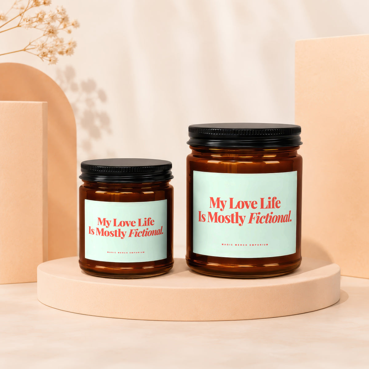 Two amber glass candles with black lids, each reading "My Love Life Is Mostly Fictional."