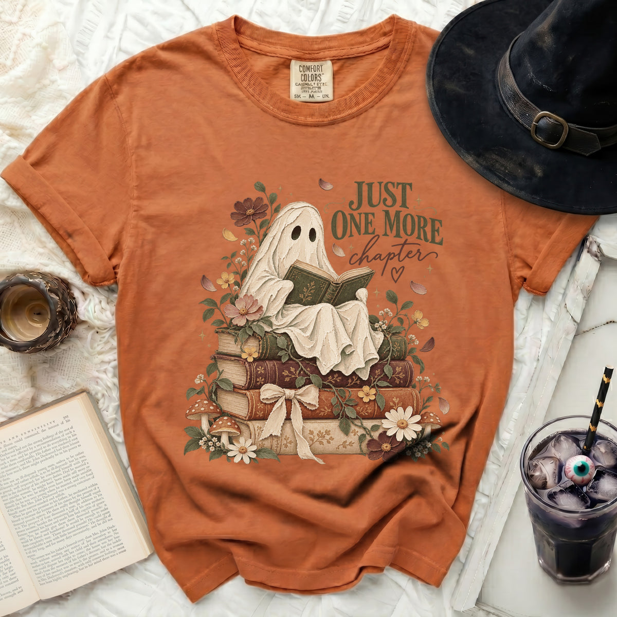 Orange t-shirt with a ghost reading a book on stacked books.