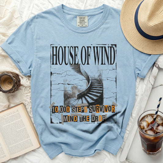 Light blue t-shirt with "House of Wind" and spiral stairs graphic, 10,000 steps survivor text.