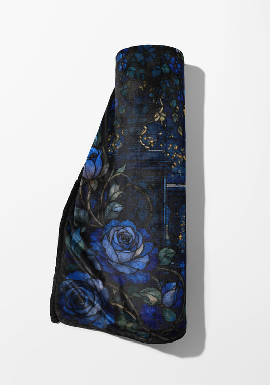 Rolled throw blanket with dark blue roses and thorny vines pattern.