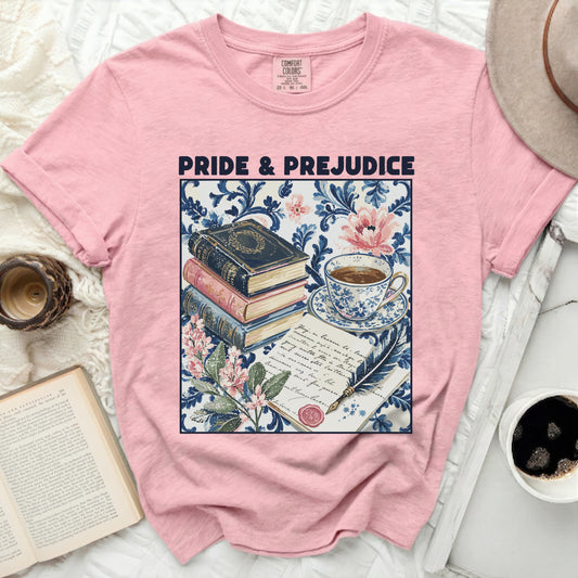 Pink t-shirt with "Pride & Prejudice" text and a vintage book stack, teacup, quill, and floral print.