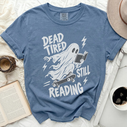 Ghost reading on skateboard with text "Dead Tired Still Reading".