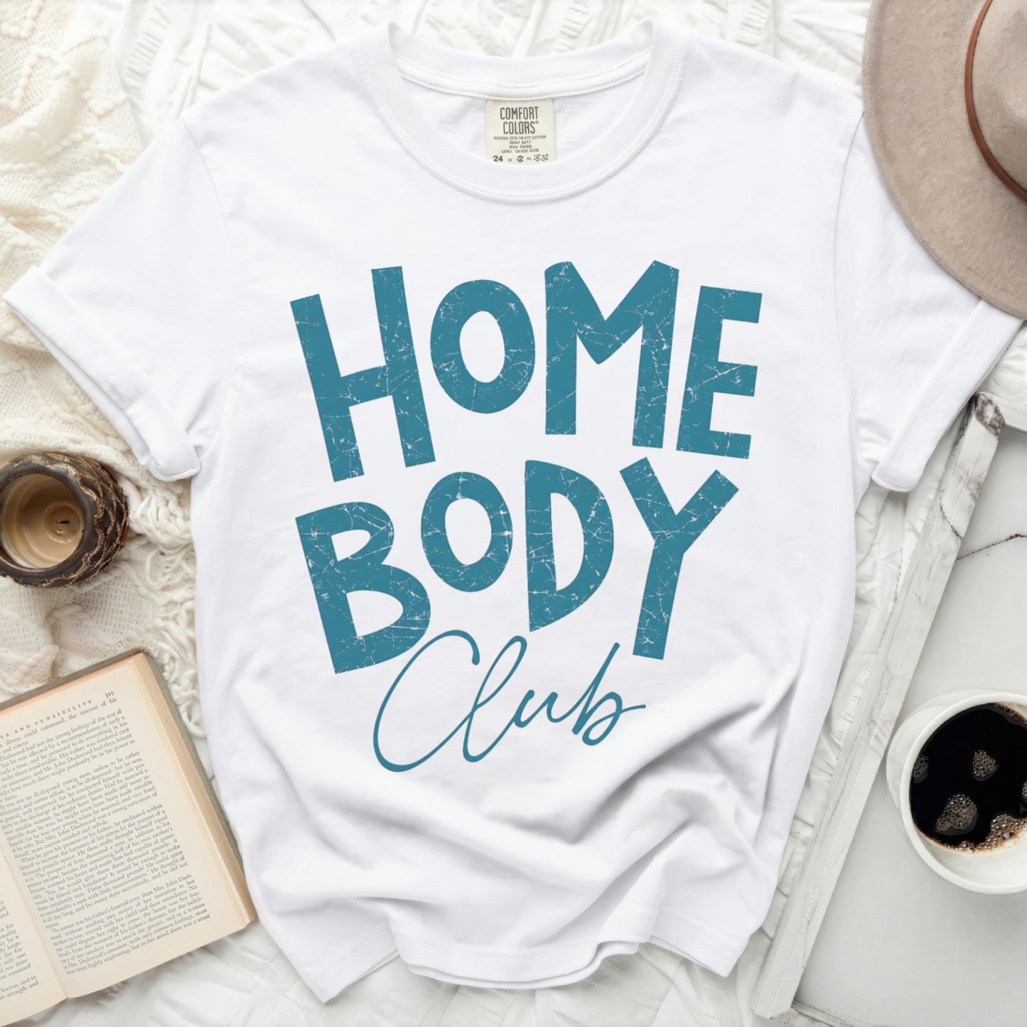 White t-shirt with "HOME BODY Club" text in distressed blue lettering.