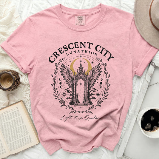 Pink t-shirt featuring a Crescent City graphic with an ornate winged archway and text.