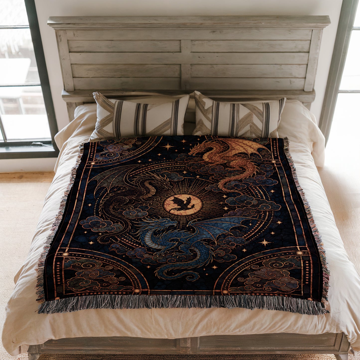 a bed with a decorative blanket featuring a dragon design, including a sun and clouds motif. The bed is set against a white wooden headboard, and there are pillows on the bed.