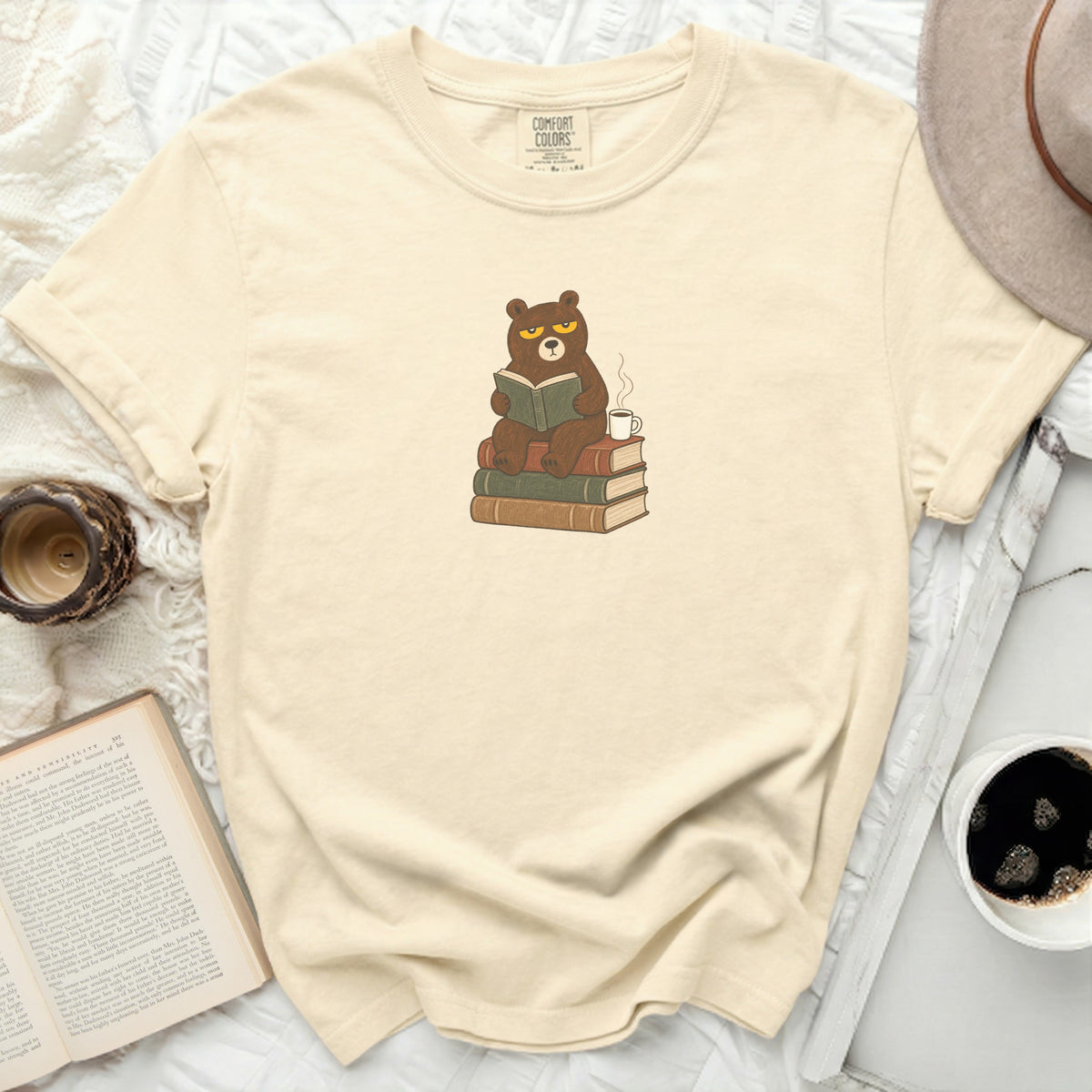 Cream t-shirt with a cartoon bear reading books and drinking coffee.