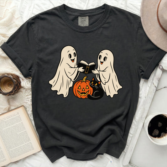 Two ghosts read a book with a pumpkin and black cat, on a dark t-shirt.