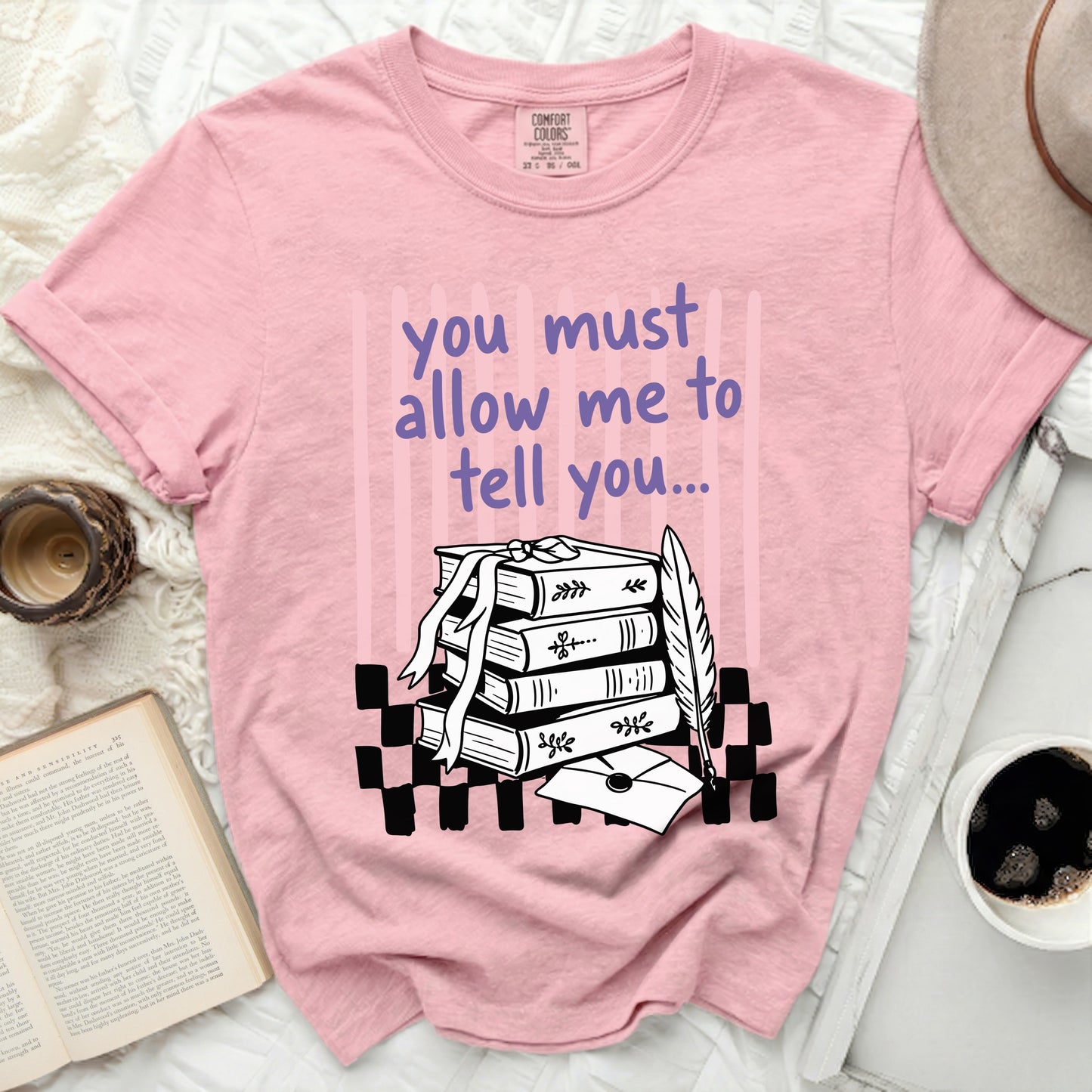 Pink shirt with "you must allow me to tell you" and stack of books design.