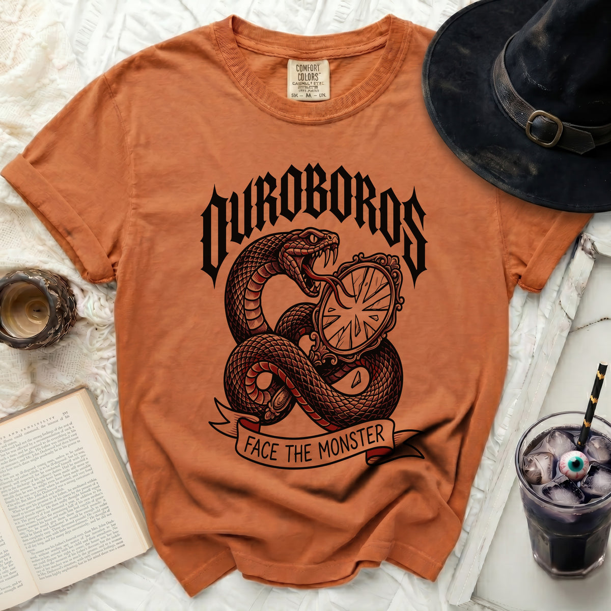 Orange t-shirt with snake and mirror graphic, text "OUROBOROS FACE THE MONSTER".
