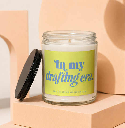 Glass candle with "In my drafting era." text on a yellow label.