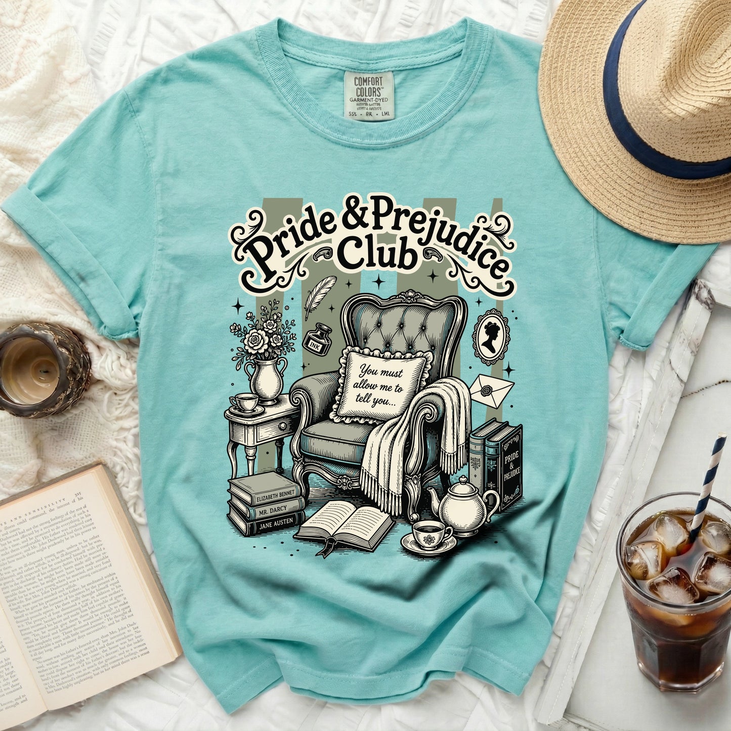 "Pride & Prejudice Club" graphic on a teal t-shirt with armchair and books.