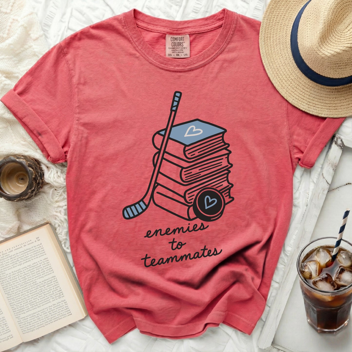 Coral t-shirt with stacked books, hockey stick, and heart puck.
