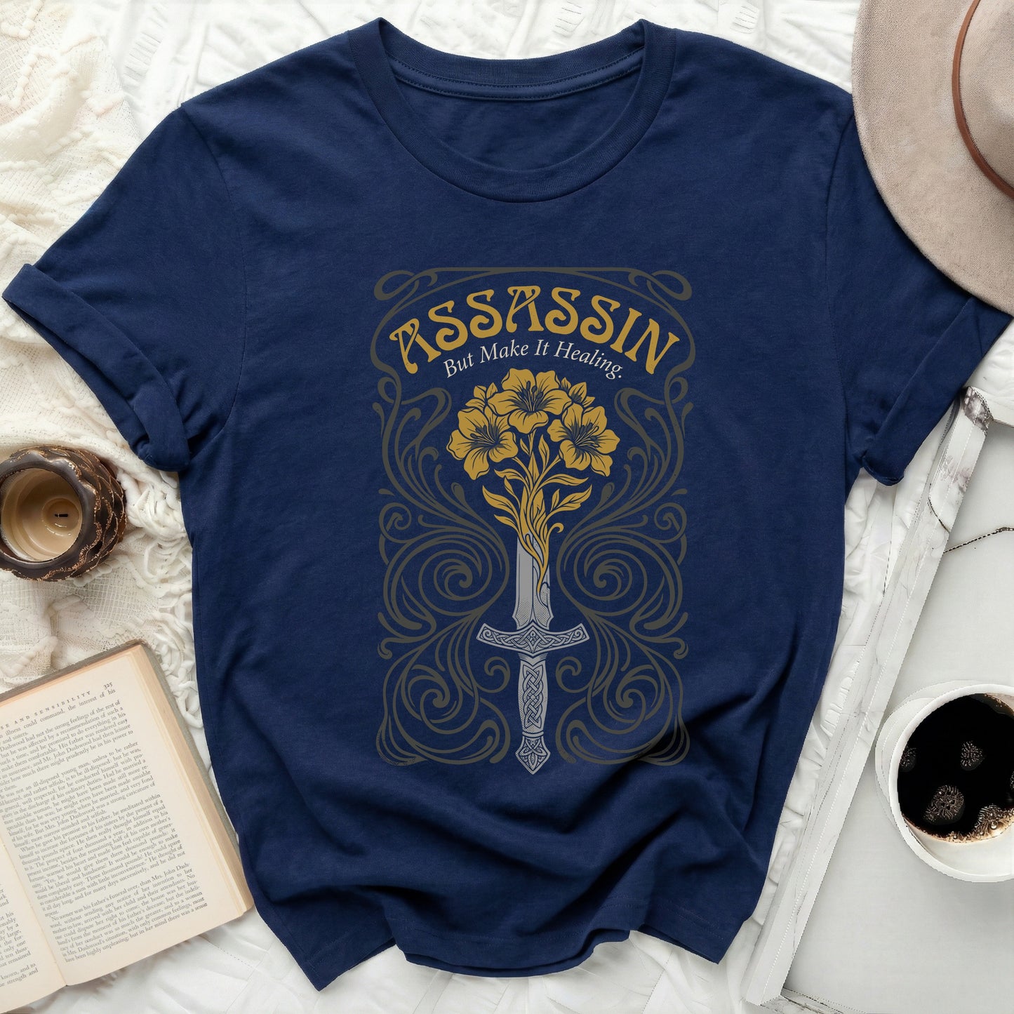 Navy t-shirt with "ASSASSIN But Make It Healing." text and sword with flowers.