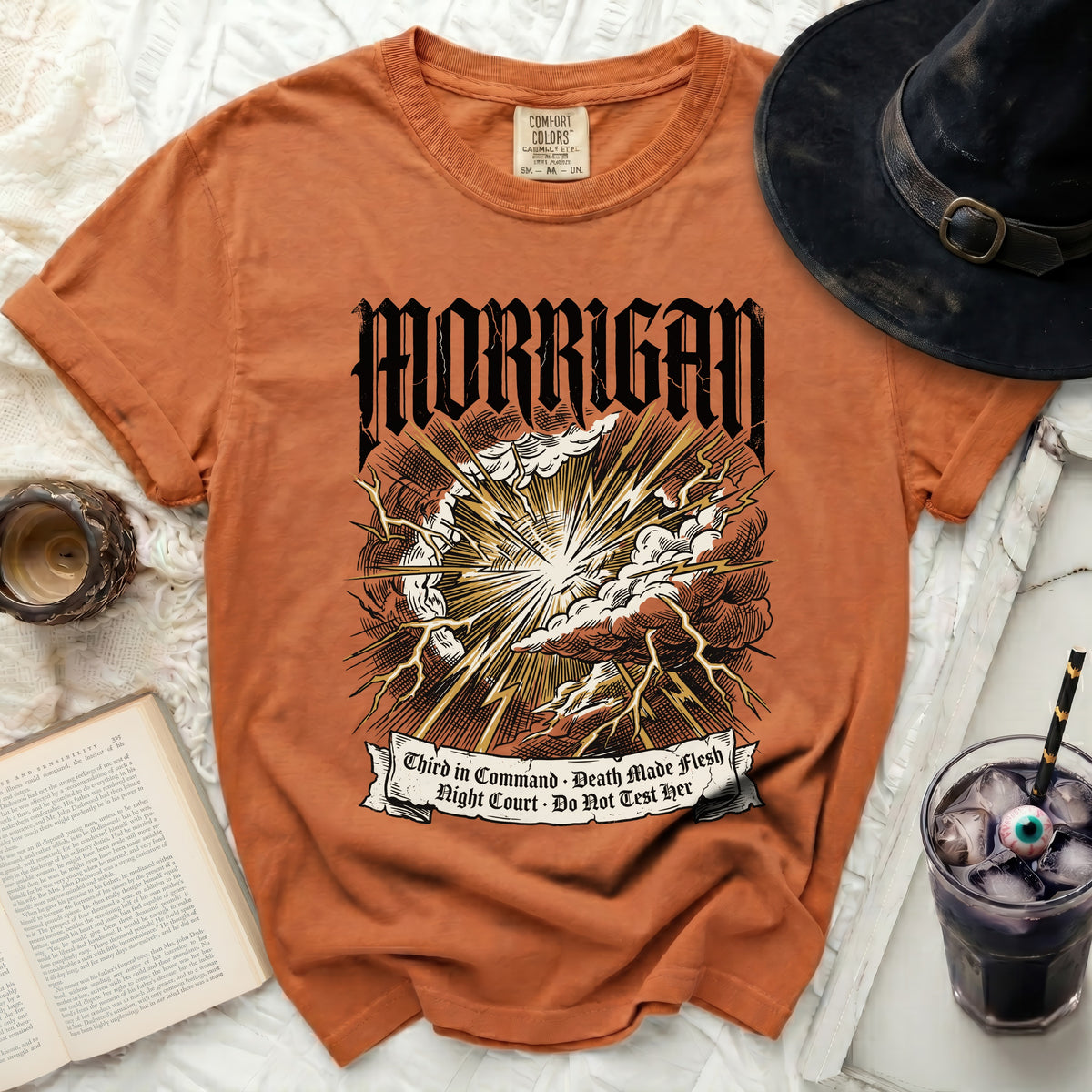 Orange t-shirt with Morrigan text, storm, lightning, and banner with quotes.