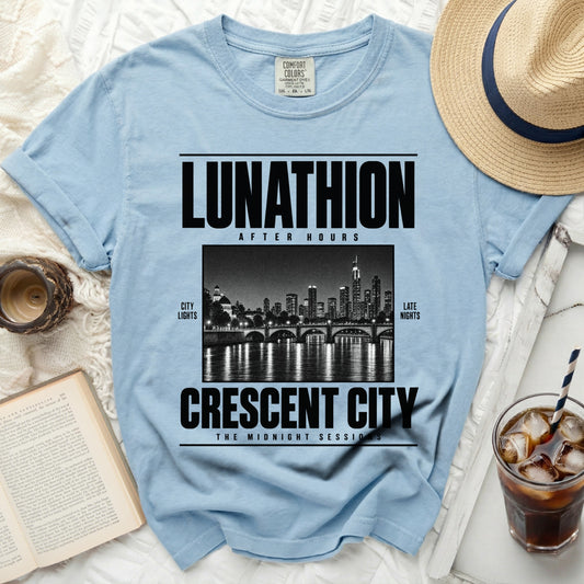 Light blue t-shirt with "LUNATHION AFTER HOURS CRESCENT CITY" text and city skyline graphic.