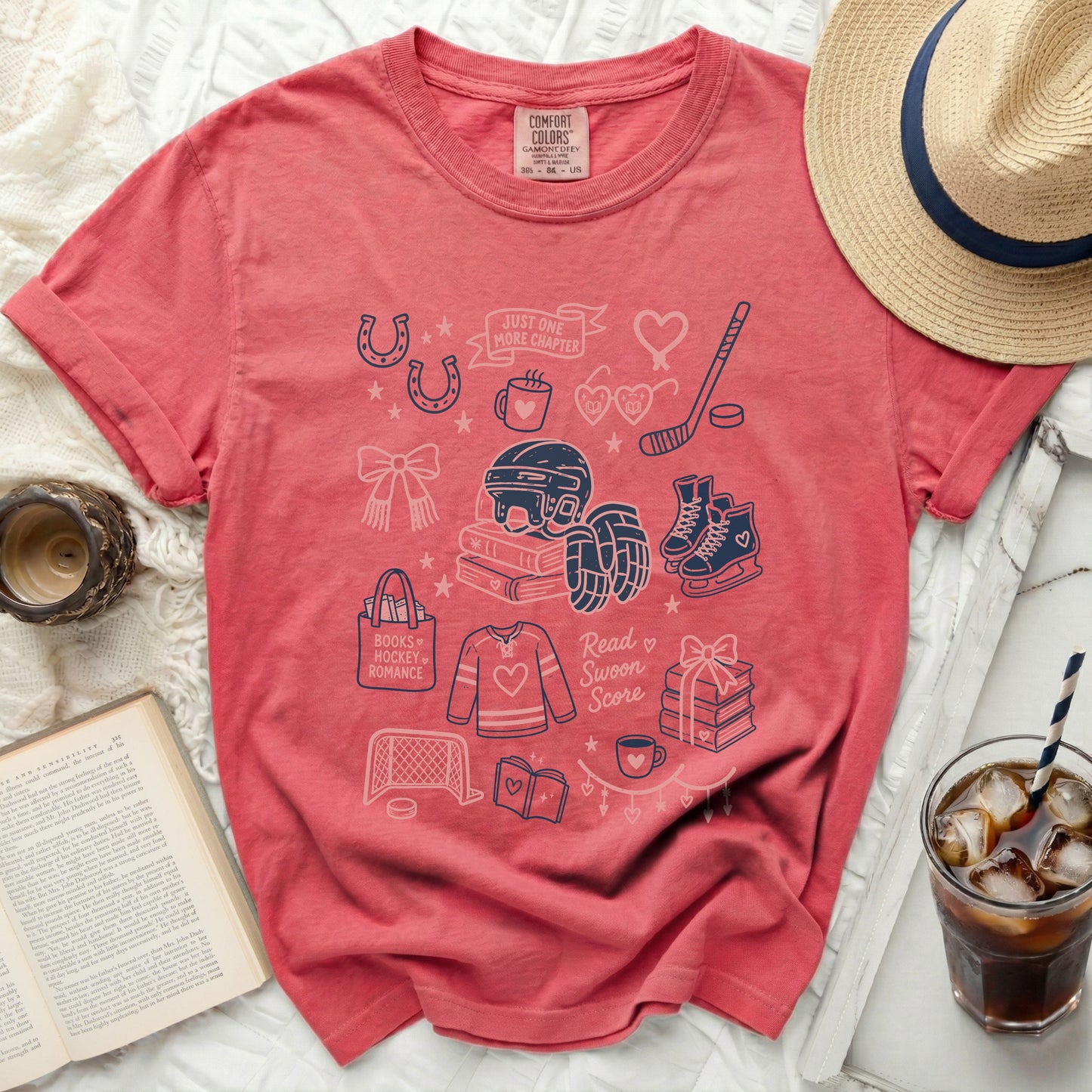 Coral t-shirt with "Just One More Chapter" and book/hockey illustrations.