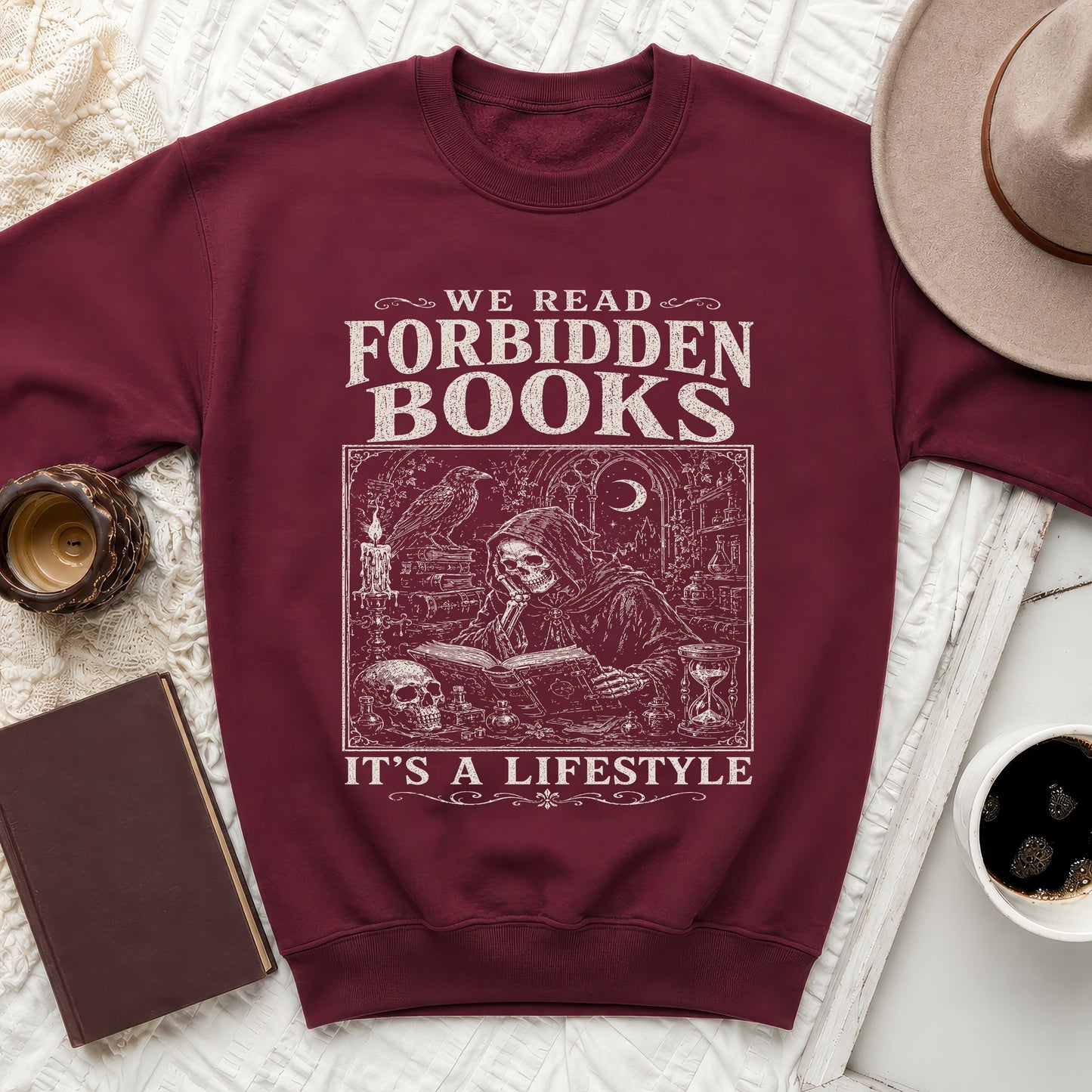 Maroon sweatshirt with graphic text "We Read Forbidden Books" and skeleton reading a book.
