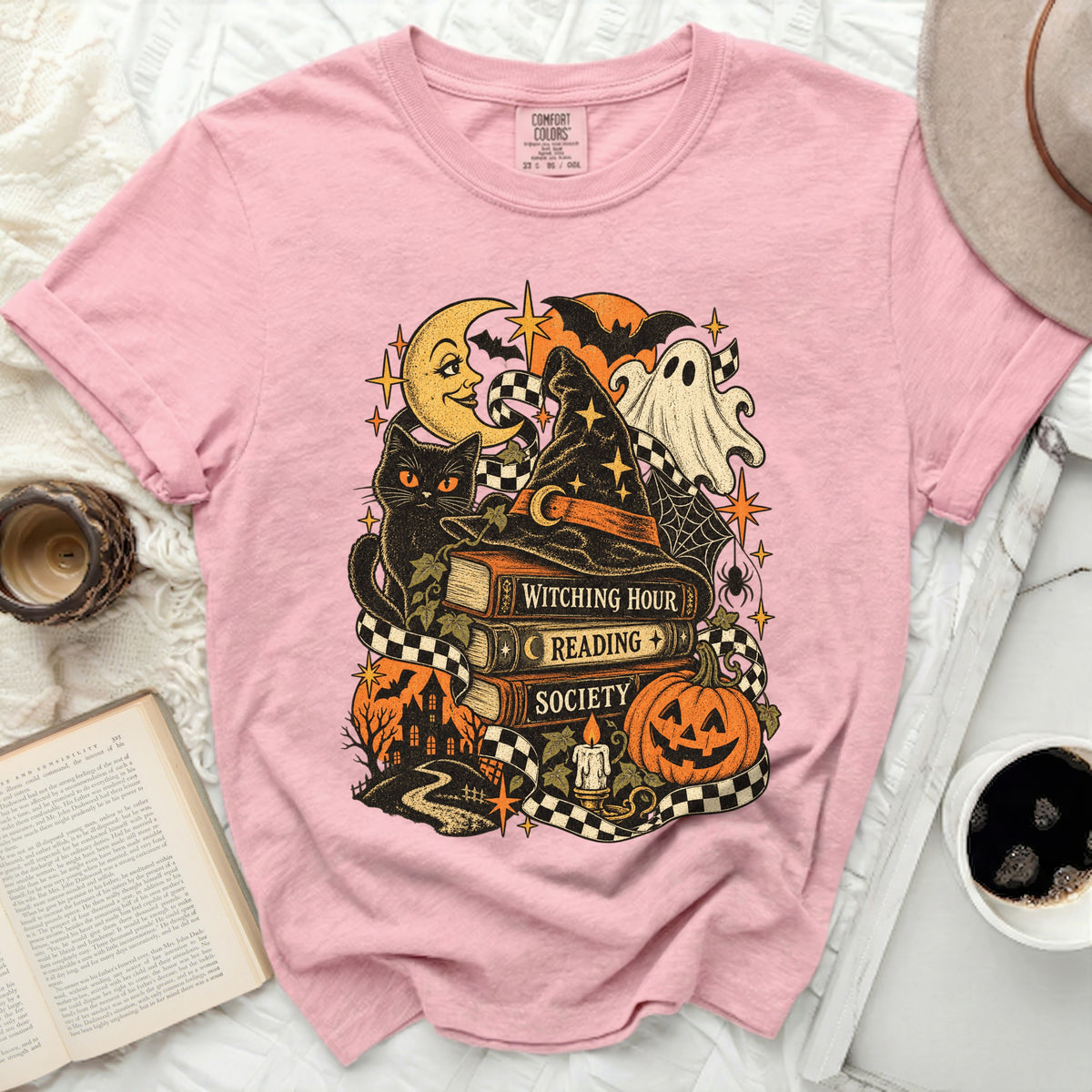 Pink t-shirt with Halloween graphic: cat, ghost, books, pumpkin, moon.
