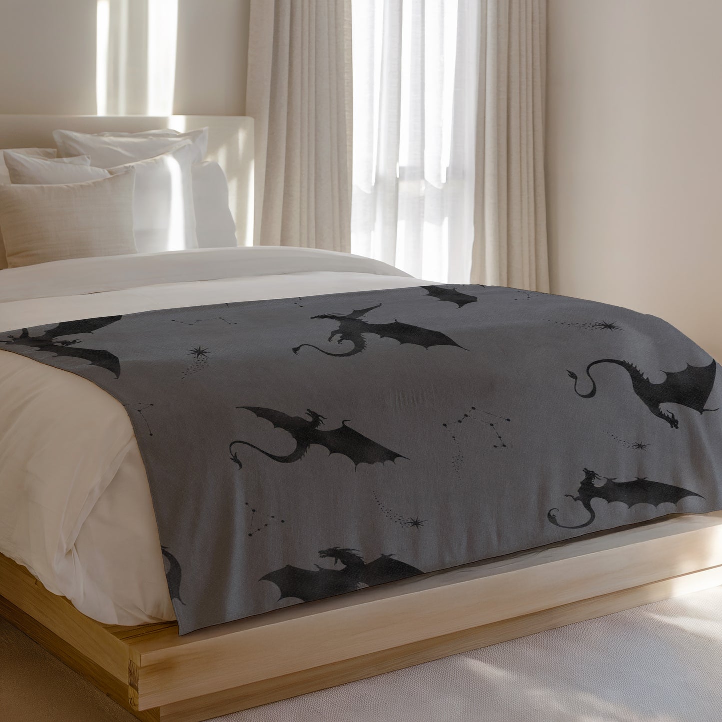 Grey blanket with a repeating pattern of black dragons and constellations.