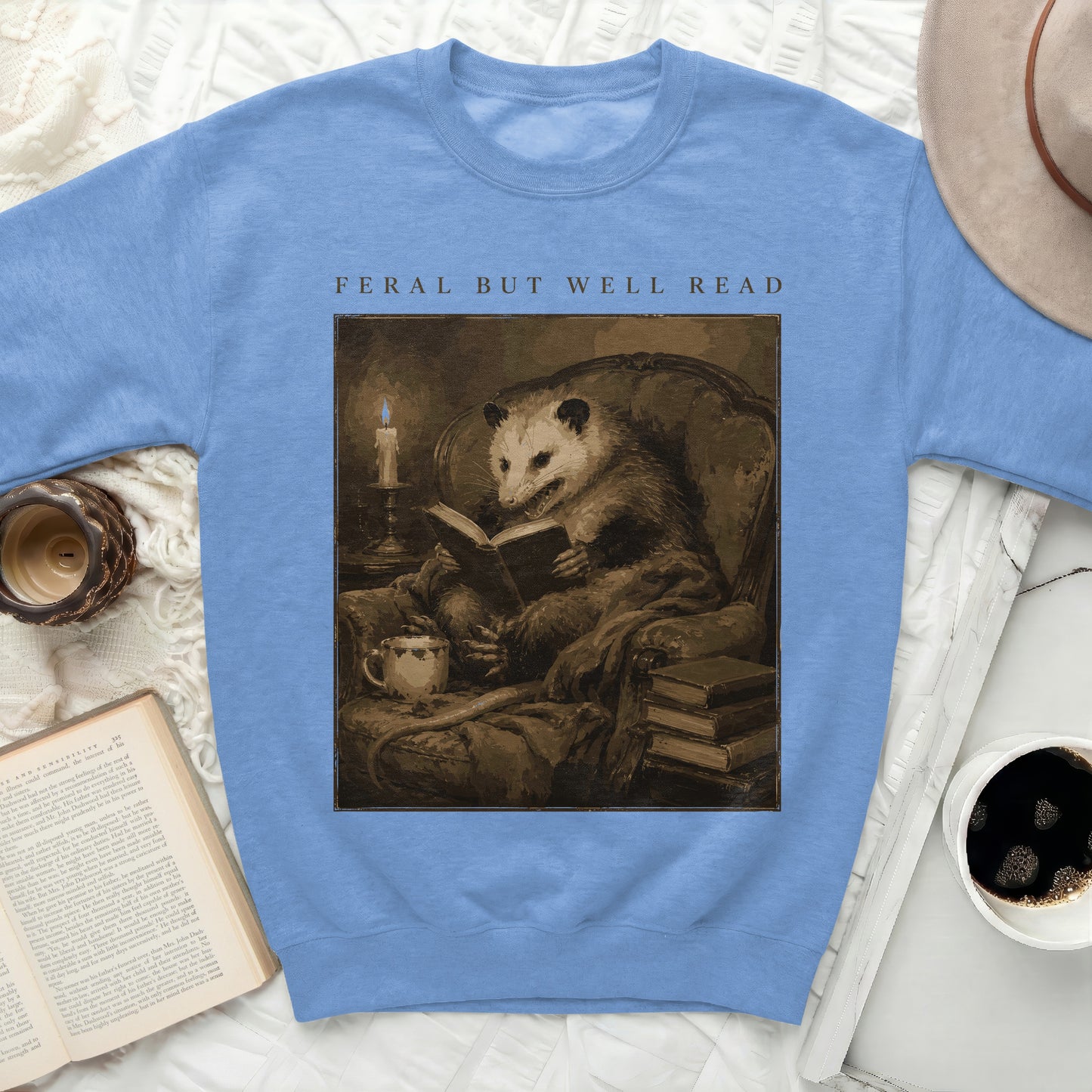 Blue sweatshirt with graphic of a possum reading "FERAL BUT WELL READ."