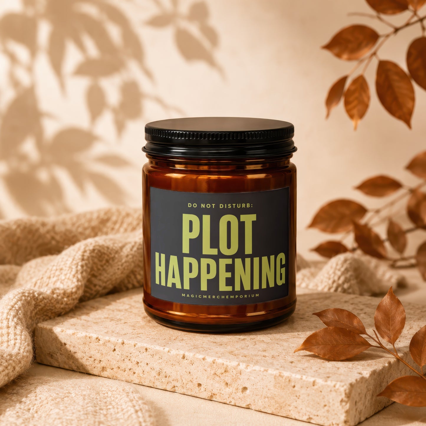 Amber candle with black lid displaying "Plot Happening" text.