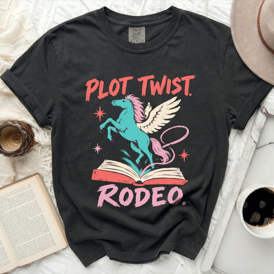 Black t-shirt with turquoise winged horse, open book, and pink text "PLOT TWIST. RODEO."