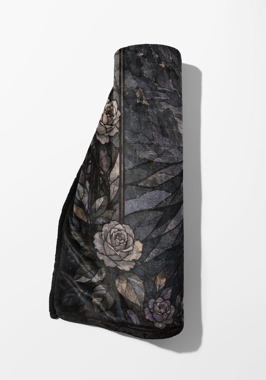 Rolled blanket with dark floral pattern featuring roses and leaves.
