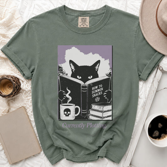 Green t-shirt with graphic of cat reading "How to Summon Snacks".