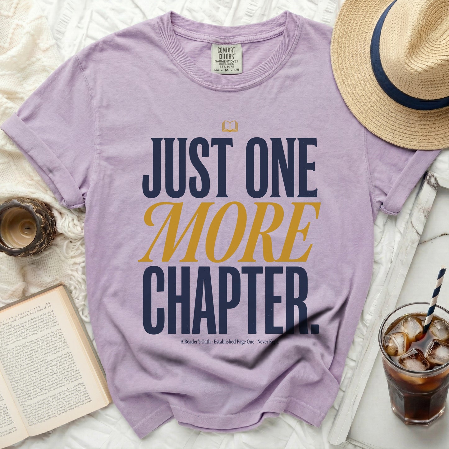 Purple t-shirt with "Just One More Chapter" text and book graphic.