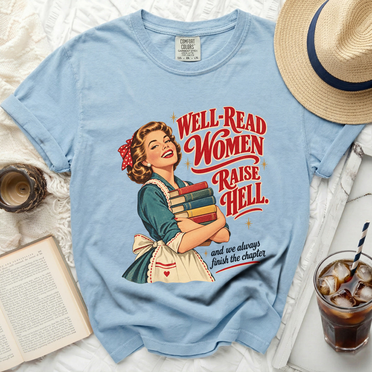 Light blue t-shirt with retro illustration of woman holding books and text "Well-Read Women Raise Hell".