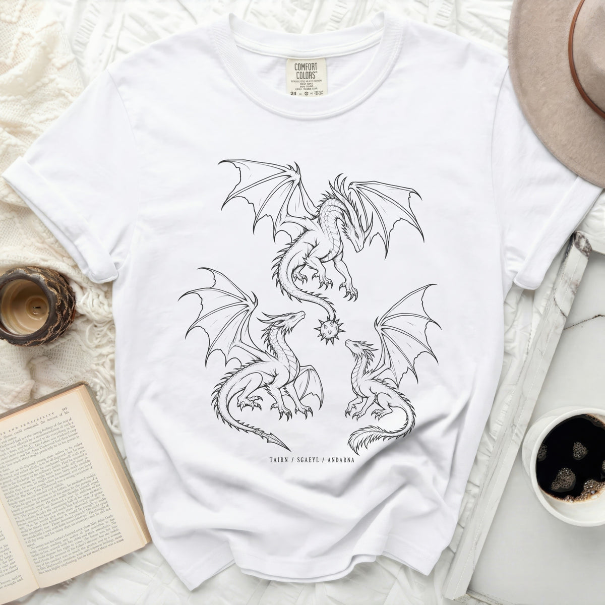 White t-shirt with three black line drawing dragons and text TAIRN / SGAEYL / ANDARNA.