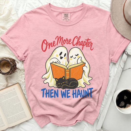 Two ghosts read a book with a black cat while a pink t-shirt reads "One More Chapter Then We Haunt."