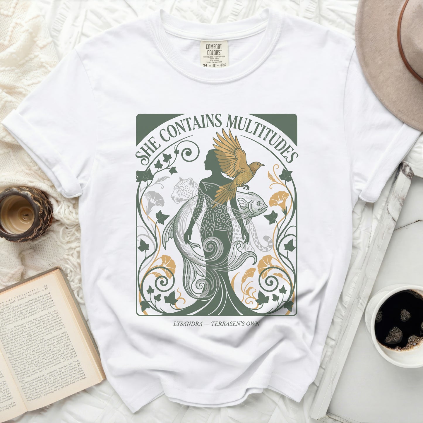 White t-shirt with "She Contains Multitudes" and mythical creatures design.