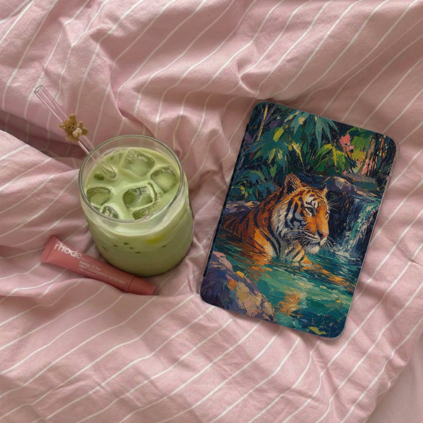 Phone case featuring artistic tiger and waterfall, with a green drink and lip balm.