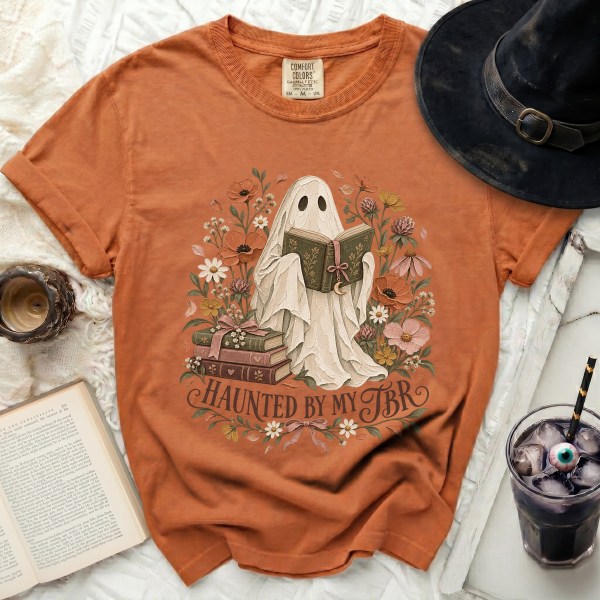 Orange t-shirt with a ghost reading a book and the words "Haunted by my TBR".