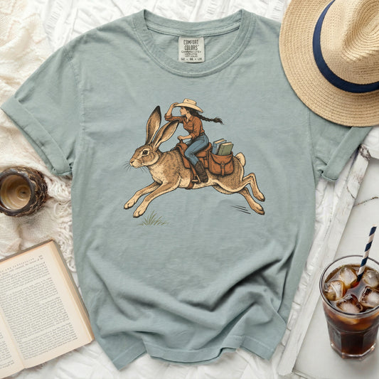 Girl riding a rabbit with books in saddlebags, on a comfort colors t-shirt.