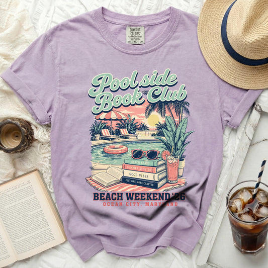 Purple t-shirt with "Poolside Book Club" text, pool scene graphic, and "Beach Weekend 26" details.