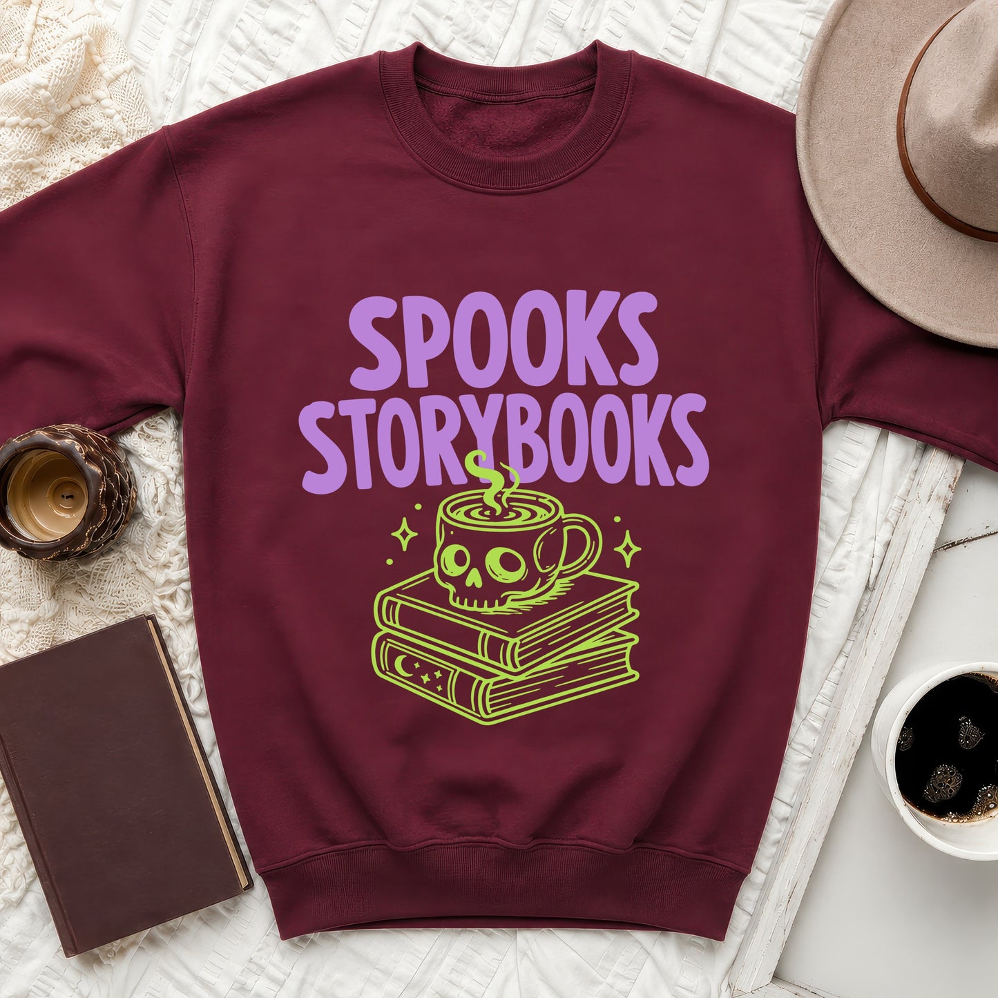 Maroon sweatshirt with "SPOOKS STORYBOOKS" text and a skull-shaped mug on stacked books.