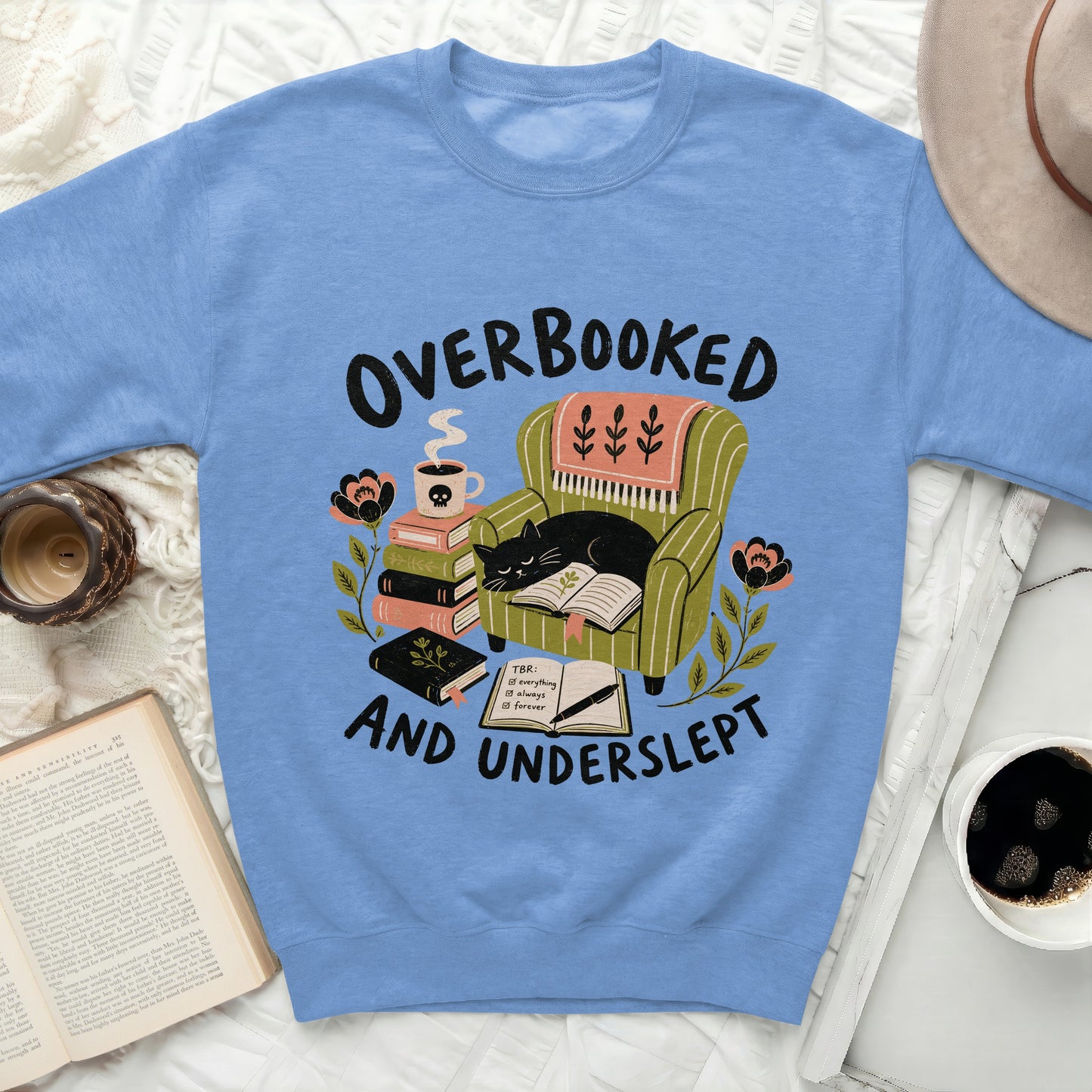 Sweatshirt with "Overbooked and Underslept" design featuring a cat in a chair.