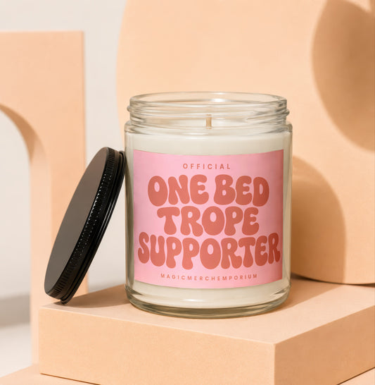 Candle with "Official One Bed Trope Supporter" text on a pink label.