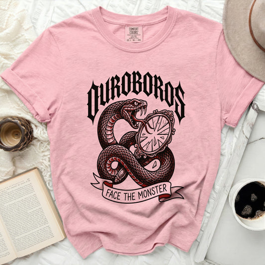 Pink t-shirt with a snake and mirror graphic that says "OUROBOROS FACE THE MONSTER".